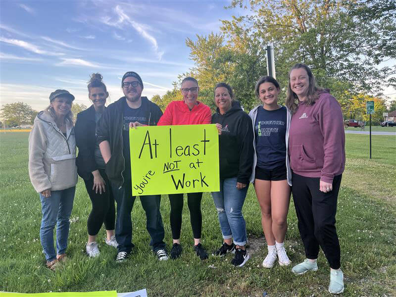 Bike to the Bay, The McAlear Group fans holding an "At least you're not at work" sign