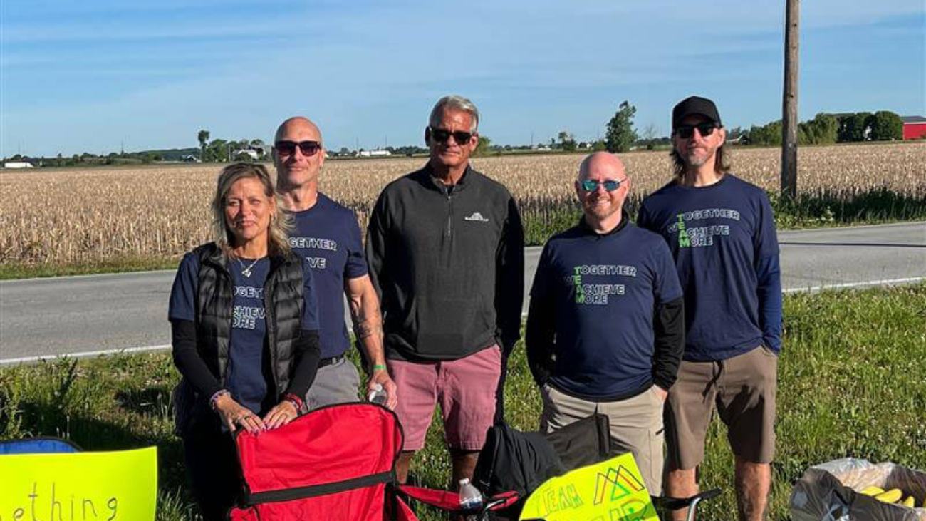 Bike to the Bay, The McAlear Group fans standing on the race sideline with their chairs, signs, and snacks, wearing "together we achieve more t-shirts"