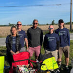 Bike to the Bay, The McAlear Group fans standing on the race sideline with their chairs, signs, and snacks, wearing "together we achieve more t-shirts"